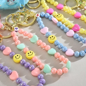 Detailed macro view of colorful macaron beaded charms with smiley face and gold clasps