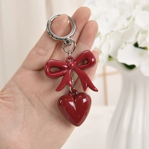 Pink heart bow keychain pendant with silver metal chain on blurred background