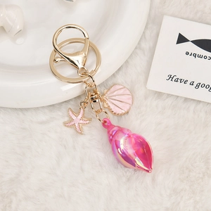 Detail of seashell starfish and conch charms on a golden metal keychain link