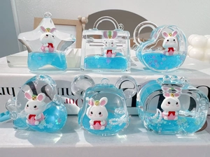 Detail of acrylic liquid quicksand charms with blue glitter and cute white bunny figures