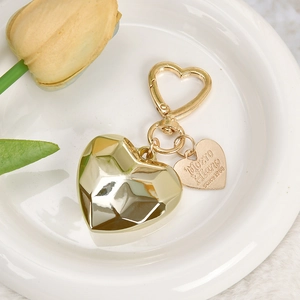 Polished gold heart keychain with 3D heart pendant and engraved tag in a ceramic bowl