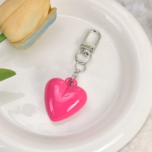 Pink heart-shaped keychain pendant with silver metal clip on a white plate with tulips