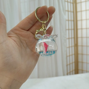 Detail of fishbowl keychain featuring pink fish, blue base, and gold lobster clasp