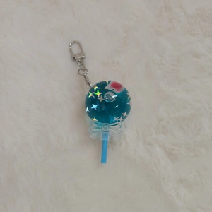 Close-up of blue lollipop acrylic keychain with glitter star filling on white fur background