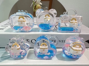 Detail of blue liquid acrylic keychains with floating glitter and white handbag charms