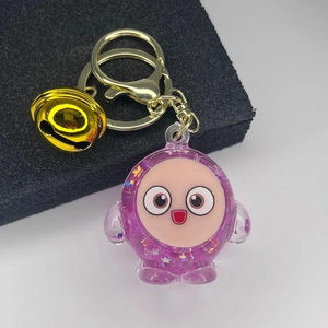 Close-up of a purple translucent glitter keychain with a golden bell and lobster clasp