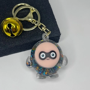 Detail of cute liquid quicksand keychain with star glitter, golden bell and spring hook