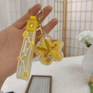 Detail eines gelben Blumen-Schlüsselanhängers mit Glitzer, Seestern und Silikonband