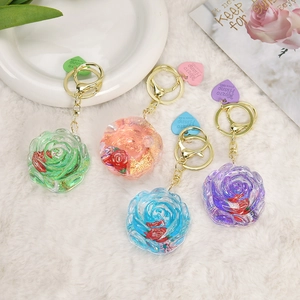 Detail of rose resin keychains with gold foil and dried flowers on soft white fur