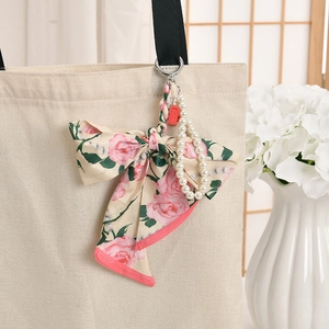 Détail du nœud en soie rose avec chaîne de perles sur un pendentif de sac à main