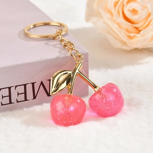 Detail of pink glitter cherry pendant with golden leaves on a soft plush background