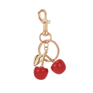 Realistic red cherry keychain with gold leaves and lobster clasp on white background