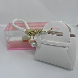 Nahaufnahme von weißem Mini-Taschen-Schlüsselanhänger mit Lederstruktur und Perle