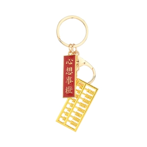 Mini golden metal abacus keychain with red lucky charm on a clean white background