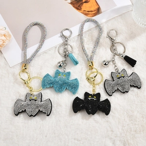 Sparkling bat rhinestone keychains with tassels and bells on soft white plush background