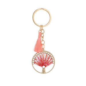 Golden tree of life pendant keychain with pink tassel and red beaded charm on white background