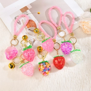 Detail of assorted resin strawberry charms with glitter rings and golden bells for keychains