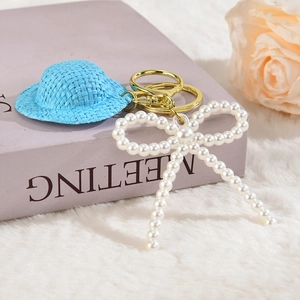 Porte-clés chapeau de paille bleu avec nœud en perles et anneau doré sur peluche douce