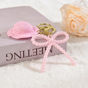 Détail d'un porte-clés mini chapeau rose avec nœud perlé et fermoir en métal doré