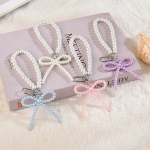 Détail de pendentifs nœuds en perles pastel avec fermoirs mousquetons argentés
