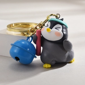Detail eines süßen Pinguin-Schlüsselanhängers mit blauer Glocke und goldenem Haken