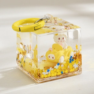 Detailed close-up of acrylic cube keychain featuring a yellow car and glitter sand