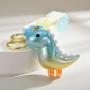 Close-up of a gradient glowing dinosaur keychain with a colorful silicone strap and golden ring