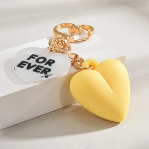 Close-up of golden heart keychain with transparent acrylic pendant and yellow heart