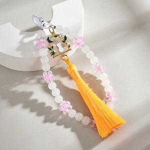 Handmade beaded peach keychain with white cat enamel pendant and yellow tassel on stand