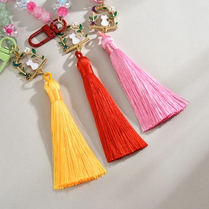 Macro detail of handmade beaded keychain featuring cat charms and colorful silk tassels