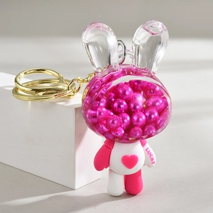 Close-up of bunny keychain with pink oil pearls, lucky lettering and gold hardware