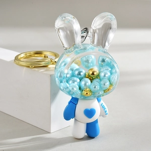 Blue acrylic rabbit keychain with liquid pearls and lucky heart on white display pedestal