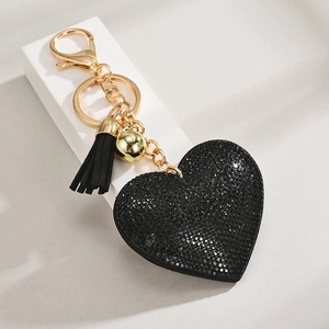 Detail of heart keychain with black glitter finish, gold clasp, and leather tassel