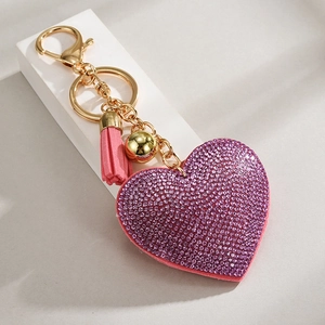Close-up of heart keychain with purple rhinestones, pink tassel and golden bell