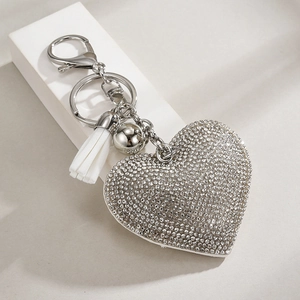 Detail of silver heart rhinestone keychain with a white tassel and lobster clasp