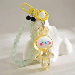 Détail d'un pendentif lapin jaune avec dragonne en perles et crochet sur fond blanc
