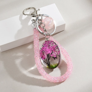 Macro detail of handmade resin pendant with pink cherry tree and butterfly crystal keychain