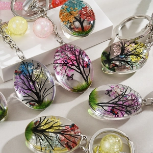 Close-up of handmade glass tree of life pendants with colorful dried flowers and butterflies