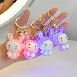 Macro shot of four glowing resin bunny keychains in pink, purple, and blue colors