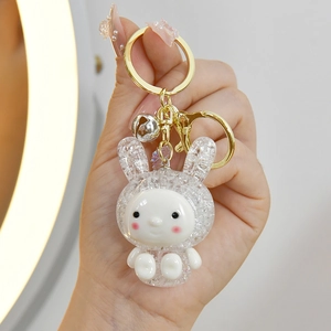 Detailed view of mini glowing bunny keychain with sparkling resin texture and gold hardware