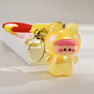 Detail of yellow translucent glowing frog keychain with gold bell and colorful strap