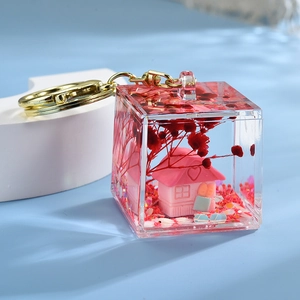 Macro shot of liquid glitter cube keychain with pink house and gold metal ring
