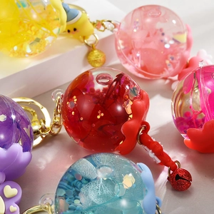 Gros plan d'un porte-clés rempli de liquide avec paillettes colorées et petit grelot
