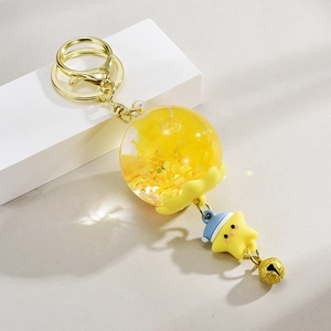 Détail du porte-clés étoile jaune avec sphère liquide, clochette et crochet doré