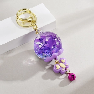 Vue détaillée d'un porte-clés boule de fleurs séchées violettes avec un petit grelot