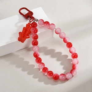 Detail of red beaded keychain with bamboo charm and metallic D-ring buckle accessory