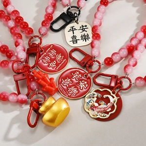 Close-up of red beaded keychain with gold charms and Chinese lucky greeting tags