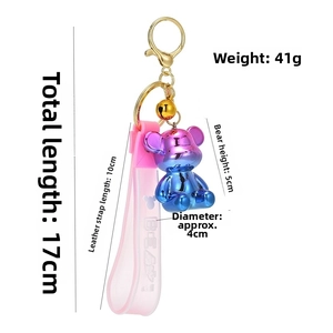 Close-up of a gradient purple bear keychain with gold bell and dimensions data