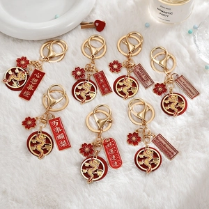Exquisite Chinese Dragon Year metal keychains with red enamel charms on white plush background