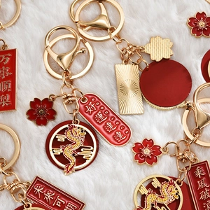 Detail of Year of the Dragon gold metal keychain with red enamel and lucky charms